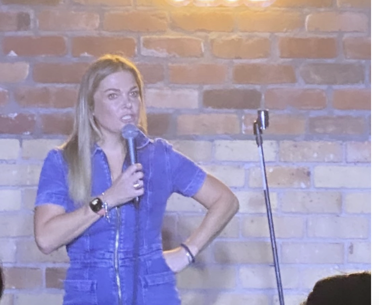 Hannah speaking with a handheld mic in front of a staircase